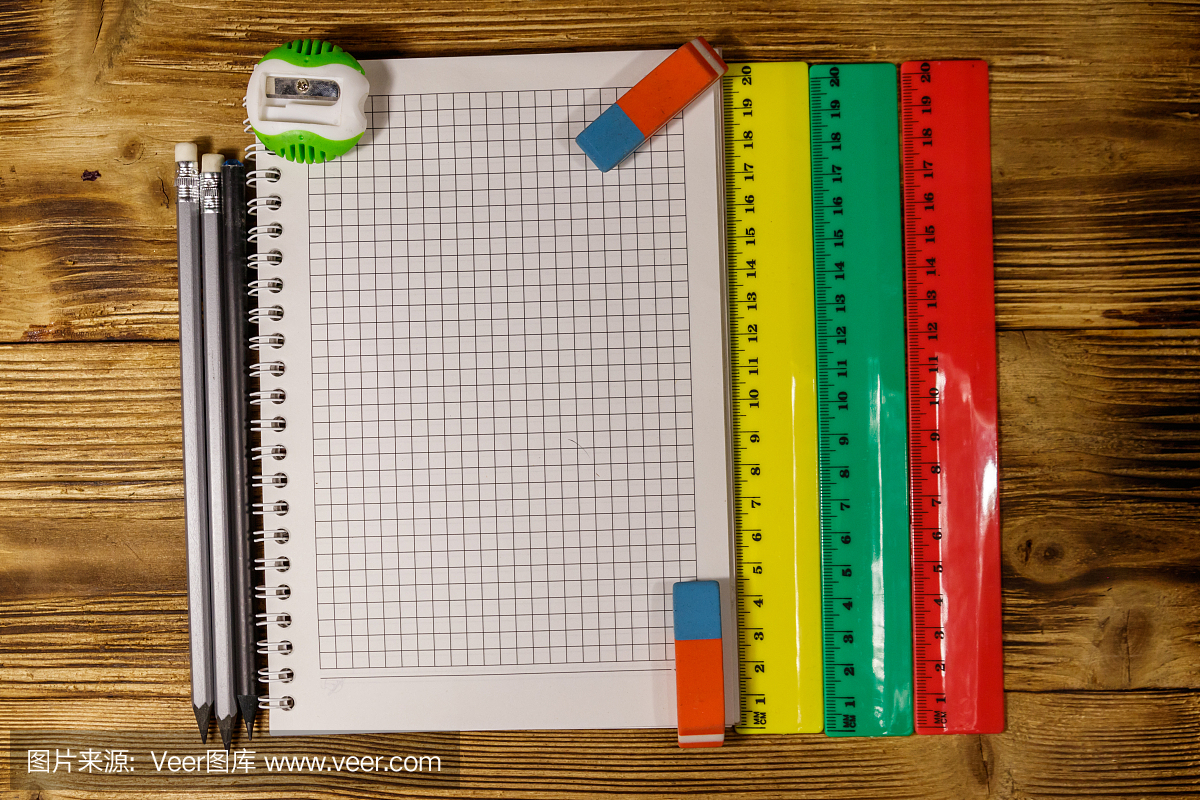整套學校文具用品。木桌上的空白記事本、尺子、鉛筆、橡皮和卷筆刀。俯視圖
