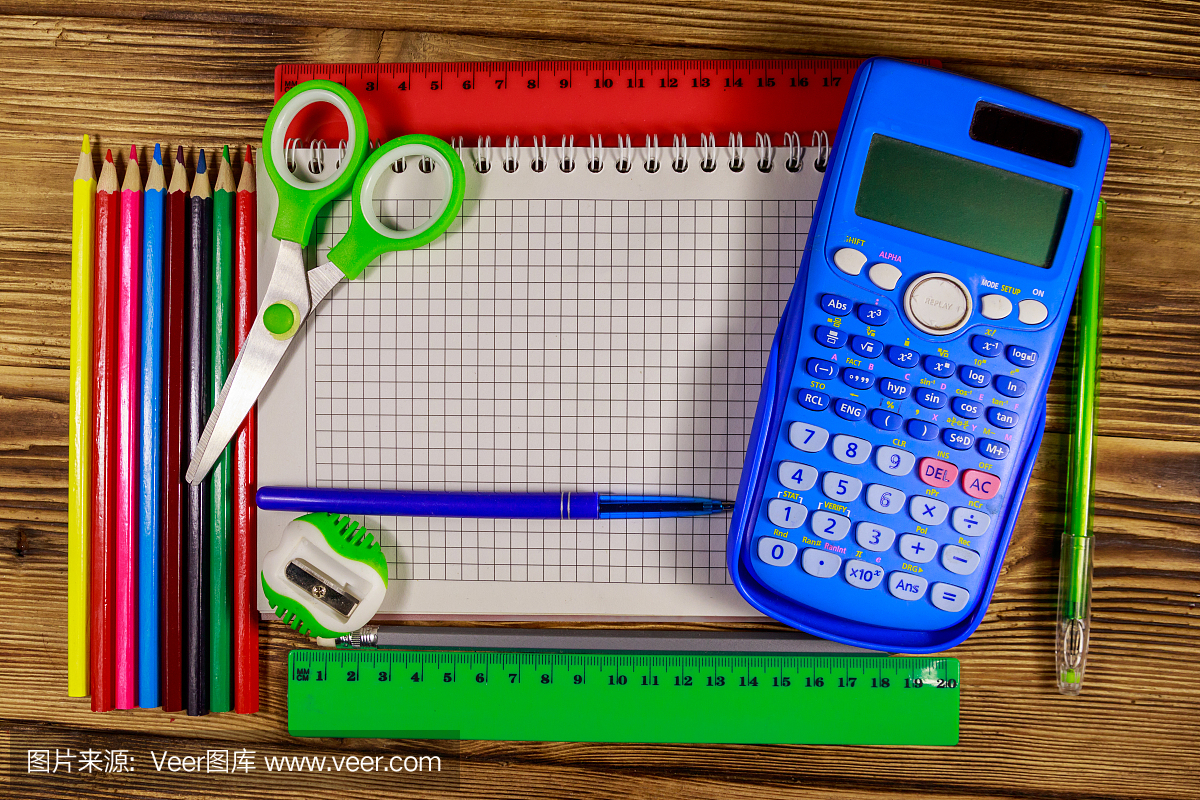 整套學校文具用品?？瞻子浭卤?計算器,尺子,鉛筆,鋼筆,剪刀和卷筆刀放在木桌上。俯視圖